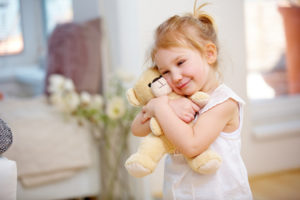 Blondes Kind kuschelt ihren weichen Teddy zu Hause